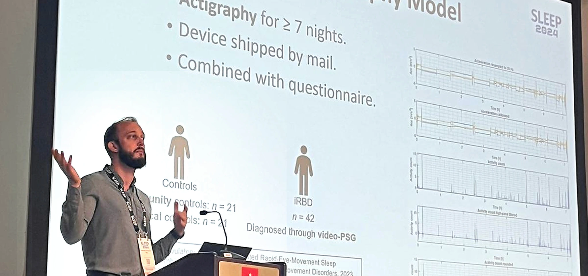 Andreas Brink-Kjær presenting a wrist-actigraphy screening model for isolated REM sleep behavior disorder, with a conference slide showing raw accelerometry signal-processing steps, SLEEP 2024.